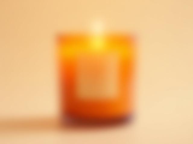 Amber glass vessel with a clean burning candle titled 'Glow - Amber & Woodsmoke'